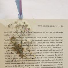 an open book with a flower on it and a blue ribbon attached to the page