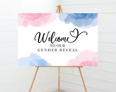 a welcome sign on an easel in front of a white wall with pink and blue watercolors