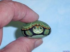 a hand holding a small turtle painted on it's face