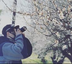 a man is taking pictures with his camera in front of some flowering trees and flowers