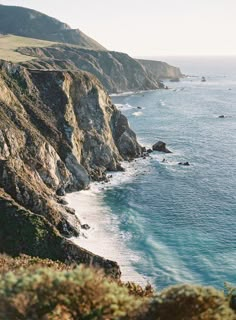 the ocean is next to some rocky cliffs