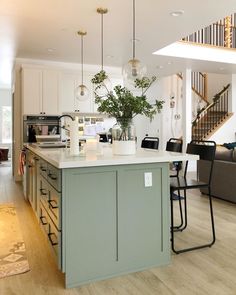 an open floor plan shows the kitchen and living room in this modern style home, with stairs leading up to the second floor