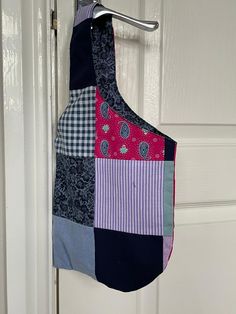 a colorful patchwork apron hanging from a door handle on a white door with a hook