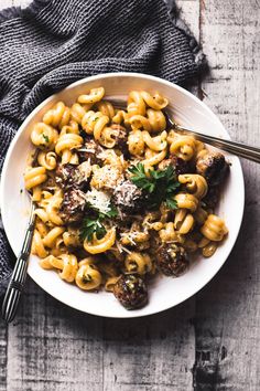 a white bowl filled with pasta and meat covered in parmesan cheese on top of a wooden table