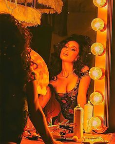 a woman sitting in front of a mirror looking at her reflection and getting ready to brush her hair