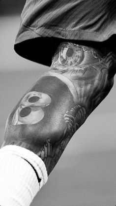 black and white photograph of a man's arm with tattoos on it, holding a skateboard