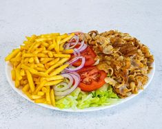 a white plate topped with french fries and salad next to sliced onion, tomato and lettuce