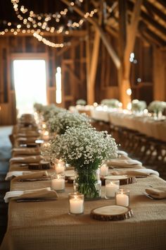 a long table with candles and flowers in vases on top of it, surrounded by lights