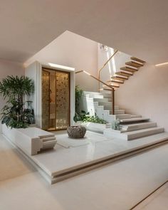 a modern house with stairs leading up to the second floor and potted plants on the other side