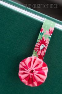 a green suitcase with a pink flowered bow on it's handle and the word, the quarter inch