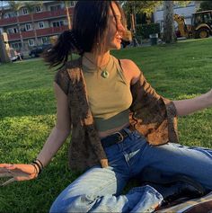 a woman sitting in the grass with her hands out