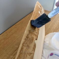 a person is using a glue stick to paint a piece of wood