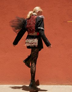 a woman walking down the street with her back to the camera, wearing black and red clothing