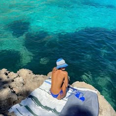 a man sitting on top of a rock next to the ocean