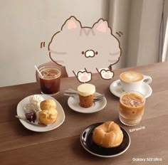 a table topped with plates of food and cups of coffee next to a cat cutout