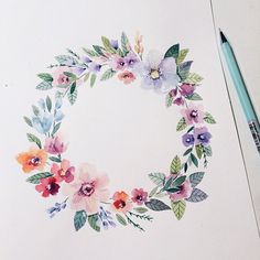 a watercolor painting of flowers and leaves in a circle on white paper with a blue marker