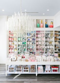 a room filled with lots of different types of crafting supplies on shelves next to a chandelier