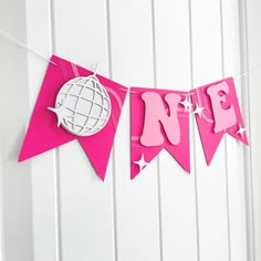 a pink banner with the word love hanging from it's side on a white wall