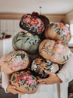 a woman is holding some doughnuts in her hands with flowers painted on them