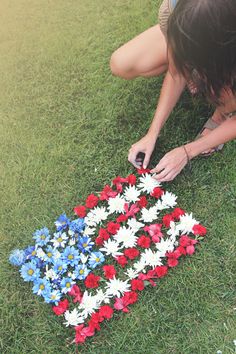 a woman laying on the ground with flowers in front of her and making a flower arrangement