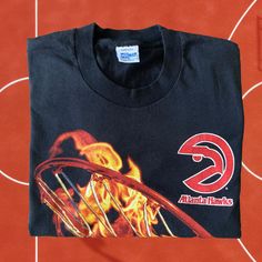 a black t - shirt with the atlanta hawks on it's front and flames in the back