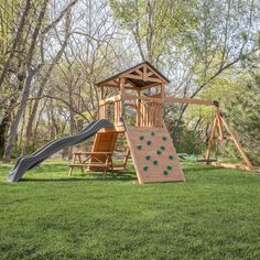 a wooden swing set and slide in the grass