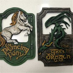 two wooden plaques depicting the green dragon and the dancing pony