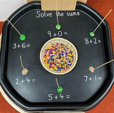 a black tray with numbers on it and some beads in the middle to solve the sums