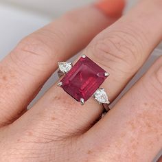 This statement ring features a stunning 5.93 carat red ruby gemstone with two natural earth mined diamonds set in solid 14K gold. This ring makes a lovely July birthstone gift for your loved ones! This ring is made with solid 14K Gold and natural Earth mined SI / G-H diamonds. As listed, this ring is ready to ship. If you're interested in purchasing this setting with a different center stone please message us! Gia Certified Ruby Ring, Formal Red Three Stone Ruby Ring, Oval Red Ruby Ring With Three Stones, Formal Red Ruby Ring With Three Stones, Formal Ruby Three Stone Ring, Luxury Three Stone Ruby Ring, Red Ruby Gemstones With Prong Setting, Luxury Ruby Three Stone Rings, Red Radiant Cut Ring With Center Stone