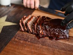 a person cutting up meat on top of a wooden cutting board