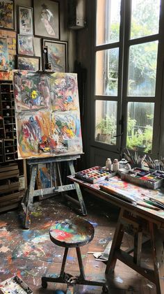 an artist's easel with lots of paint on it in front of a window