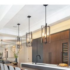 a kitchen filled with lots of counter top space and lights hanging from the ceiling above it