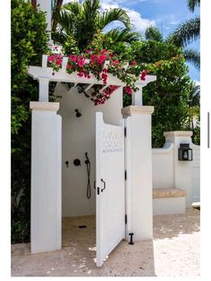 an open white door with pink flowers hanging from it's sides and on the outside