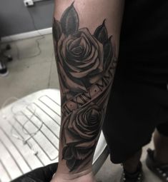 a black and grey rose tattoo on the left arm with words written in cursive font