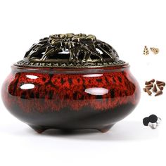 a red and black vase sitting on top of a white table next to other items