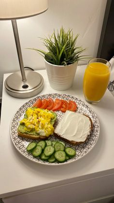 a plate with toast, cucumbers and tomatoes on it next to a glass of orange juice