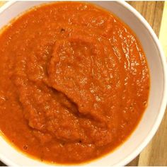 a white bowl filled with red sauce on top of a wooden table