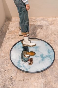 a man standing on top of a round mirror with his feet in the air,