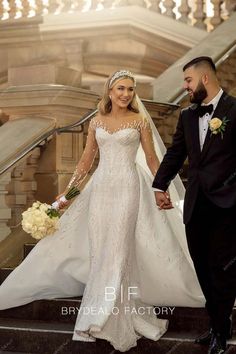 the bride and groom are walking down the stairs together in their wedding gowns with beaded detailing