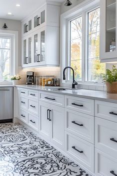 a kitchen with white cabinets, black and white flooring and an ornate tile pattern on the floor