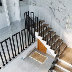 the stairs are made of wood and have black railings on each side, along with a carpeted doormat