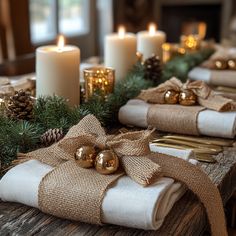 the table is set for christmas with candles and burlap wrapped presents on it