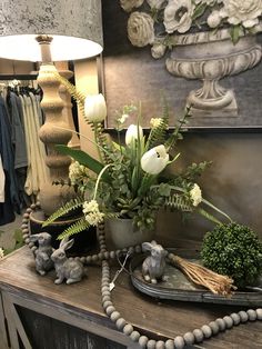 a vase with white flowers and greenery sits on a table next to other items