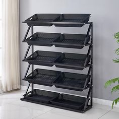 a black shelf with baskets on it in front of a potted plant