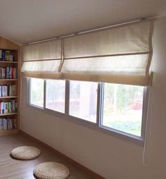 a living room with three bookshelves and two round rugs on the floor