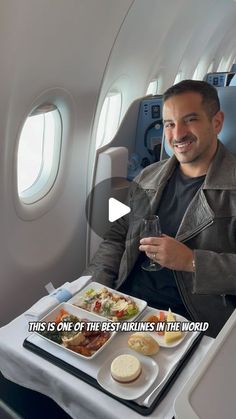 a man sitting in an airplane with food on the tray