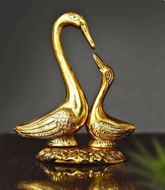 two golden swan figurines sitting on top of a table