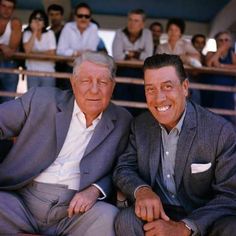 two men sitting next to each other in front of a crowd