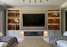 a living room with two white couches and a flat screen tv mounted on the wall