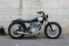 a black and white motorcycle parked next to a wall